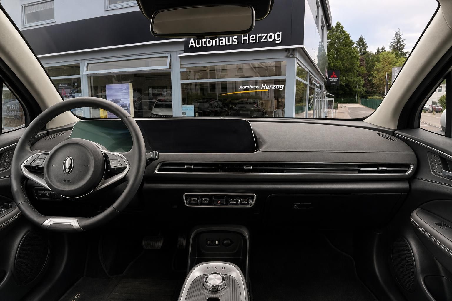 Fahrzeug-Innenraum mit modernem Dashboard, Lenkrad und Mittelkonsole in dunkler Ausstattung