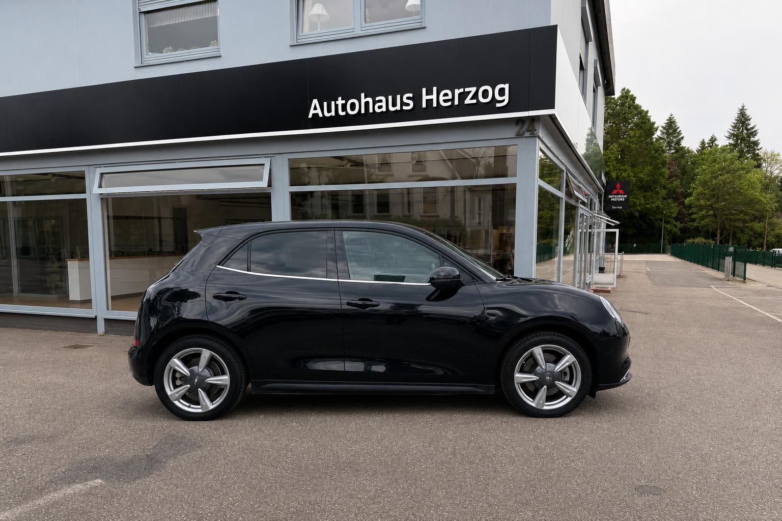 Schwarzer Kompaktwagen Seitenansicht vor Autohaus - modernes Elektrofahrzeug mit Alu-Felgen