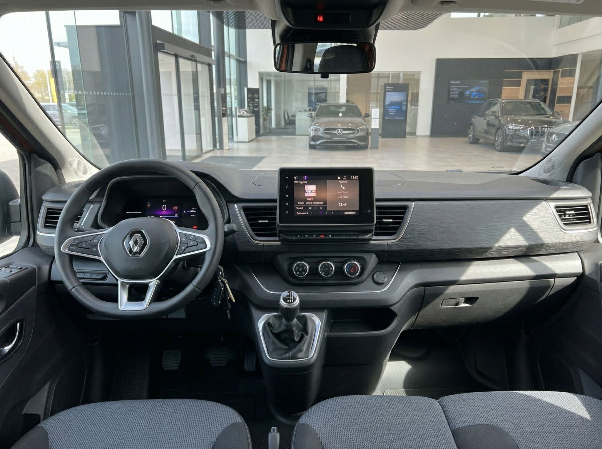 Renault Fahrzeug Innenraum mit Lenkrad, Touchscreen und Blick auf Autohaus Showroom