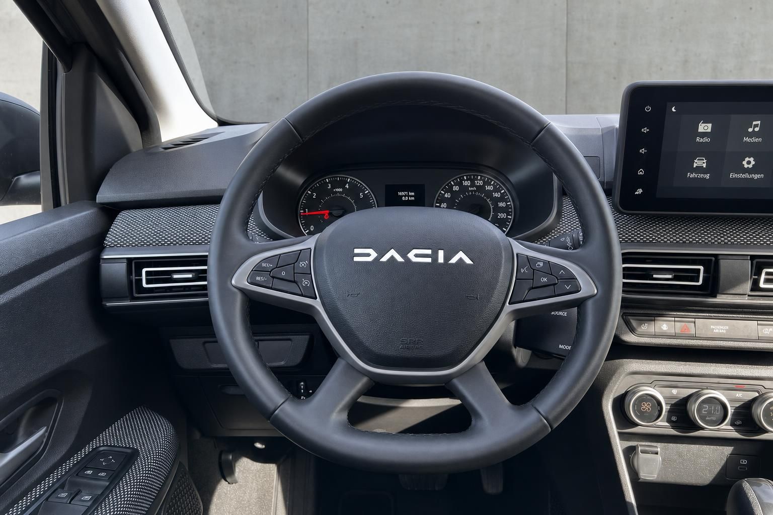 Cockpit mit DACIA-Lenkrad, Tacho und Touchscreen-Display im Fahrzeuginnenraum
