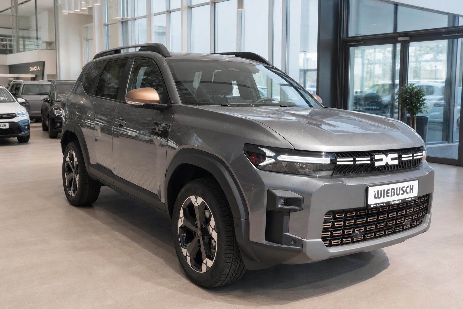 Dacia Bigster SUV in grau, Schrägansicht vorne rechts im Autohaus-Showroom