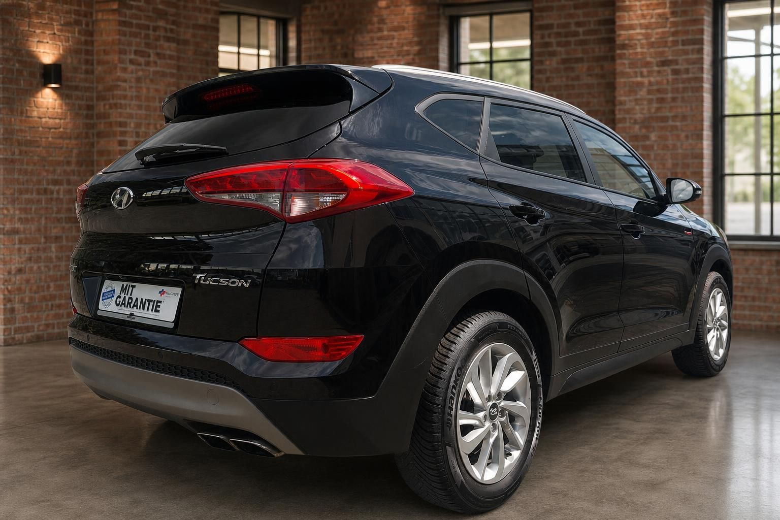 Hyundai Tucson schwarz Heckansicht schräg links im Showroom – SUV mit Dachspoiler und Alufelgen