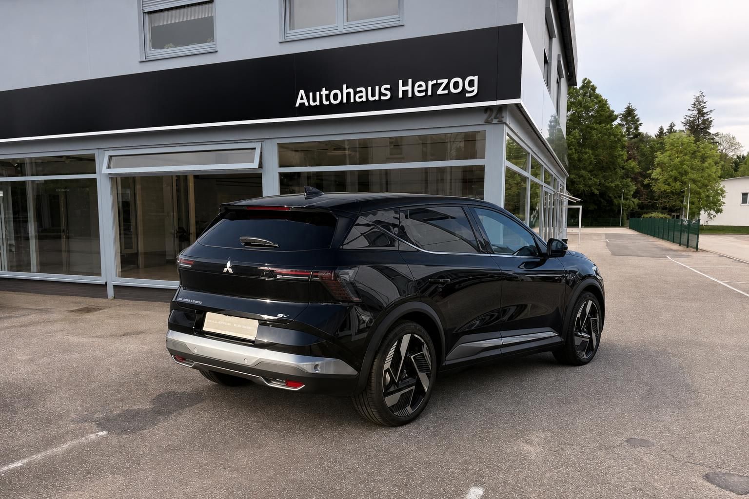 Mitsubishi Eclipse Cross schwarz - Schrägansicht hinten mit Autohaus Herzog im Hintergrund