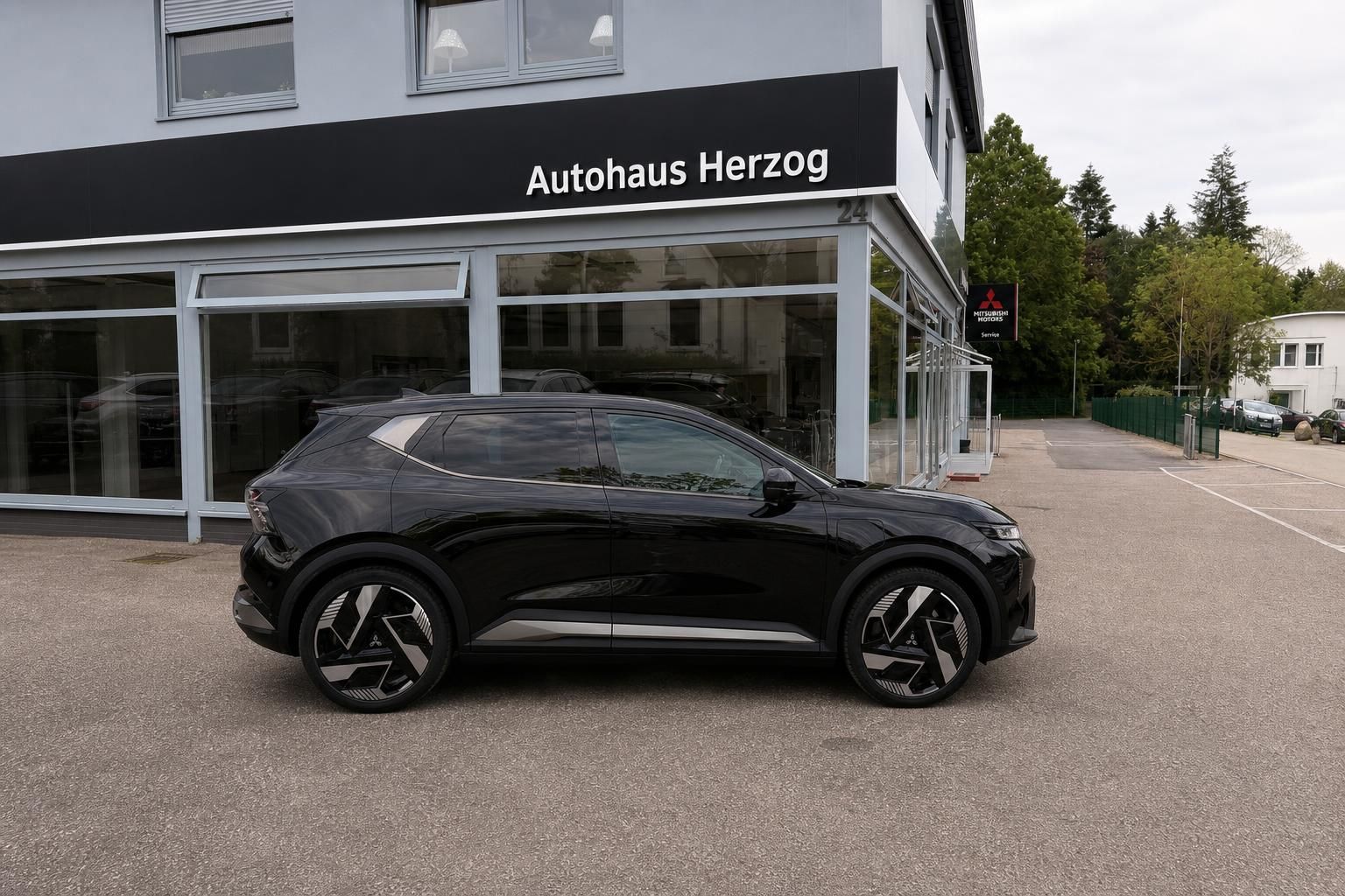 Schwarzer SUV Seitenansicht vor Autohaus Herzog - modernes Elektrofahrzeug mit auffälligen Felgen