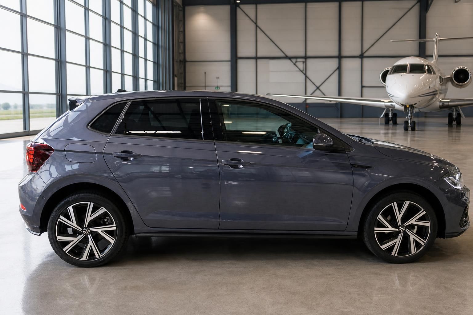 VW Polo R Seitenansicht rechts dunkelblau metallic im Hangar mit Privatjet im Hintergrund