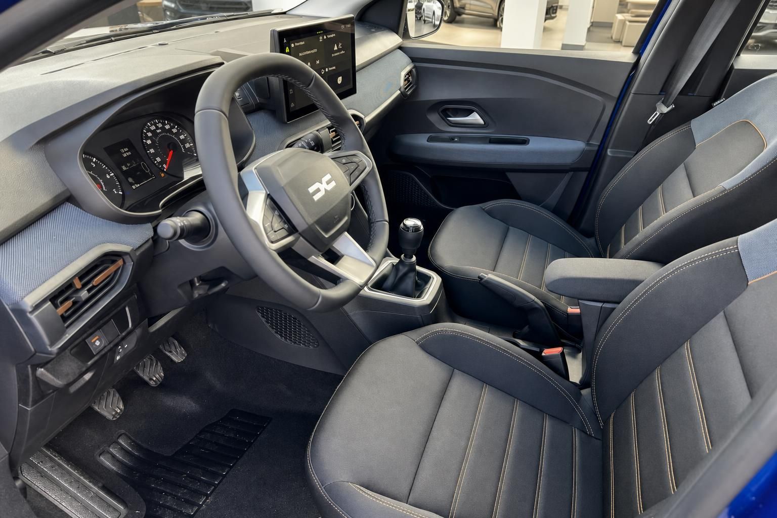 Moderner Fahrzeuginnenraum mit Lenkrad, Touchscreen-Display und grauen Sportsitzen im Autohaus