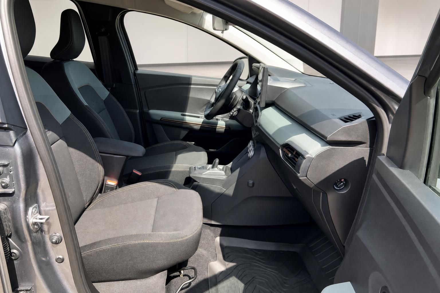 Fahrzeug Innenraum mit grau-schwarzen Sitzen, Armaturenbrett und offener Beifahrertür