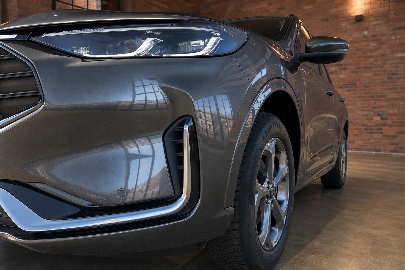 Ford Kuga SUV grau – Detailaufnahme Front mit LED-Scheinwerfer und Felge in Ausstellungsraum