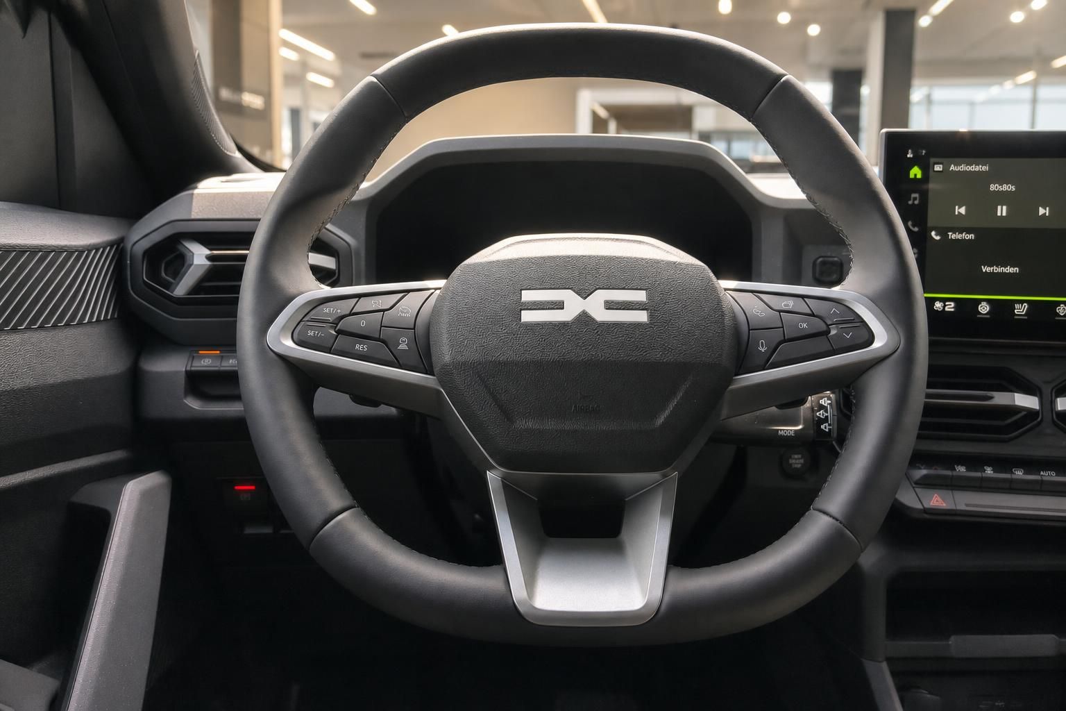 Lenkrad mit Multifunktionstasten und Infotainment-Display im Fahrzeuginnenraum
