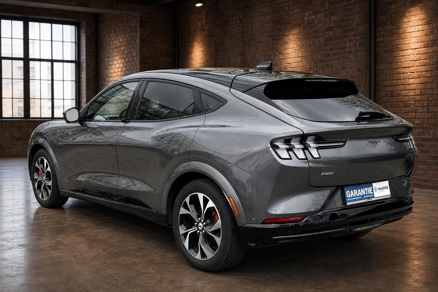 Ford Mustang Mach-E in Grau, Heck-Seitenansicht in Industrie-Loft