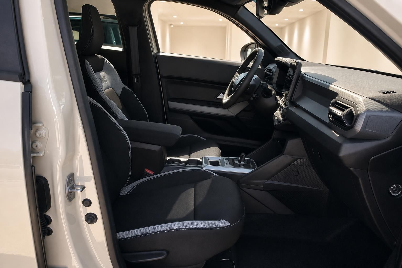 Dacia Innenraum Vordersitze schwarz mit Mittelkonsole und Lenkrad – Fahrerbereich