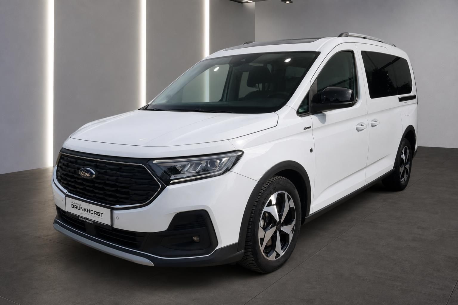 Weißer Ford Tourneo Van in modernem Autohaus Showroom - Seitenansicht mit Allwetterrädern