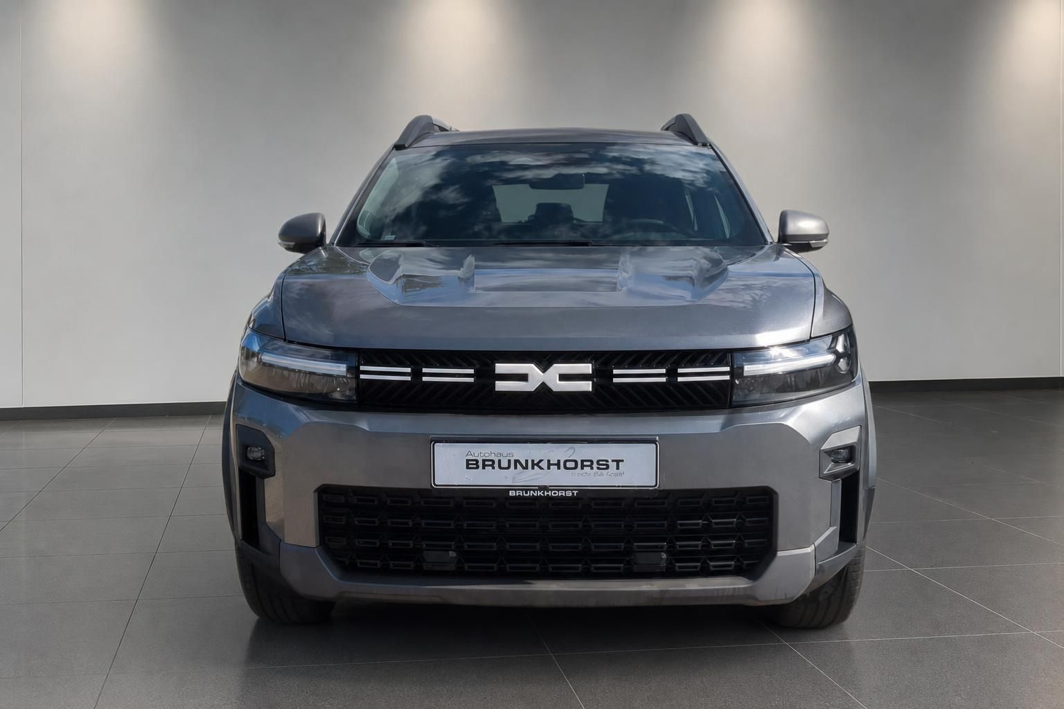 Dacia Bigster SUV Frontansicht in Grau vor weisser Wand im Showroom