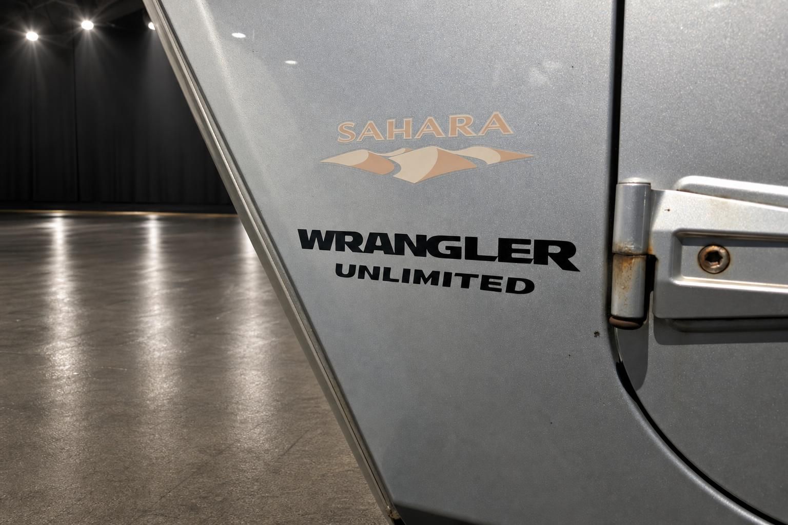Detailaufnahme Jeep Wrangler Sahara Unlimited Seitenbeschriftung und Logo auf silberner Karosserie