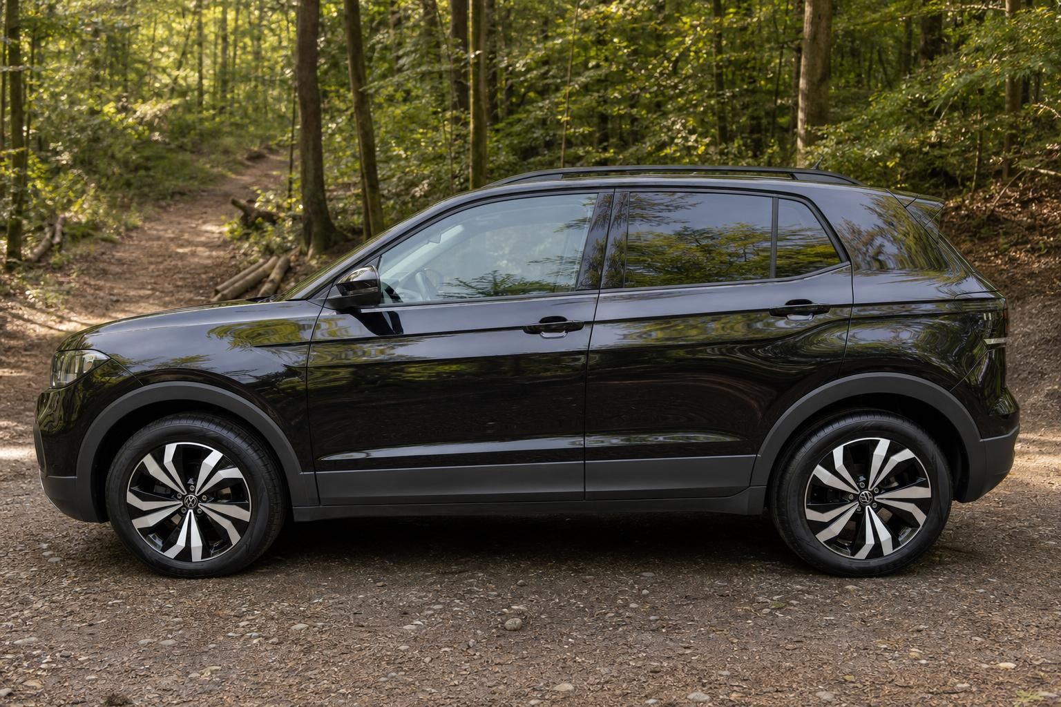 Volkswagen T-Cross SUV schwarz - Seitenansicht mit Designfelgen und Seitenprofil im Wald