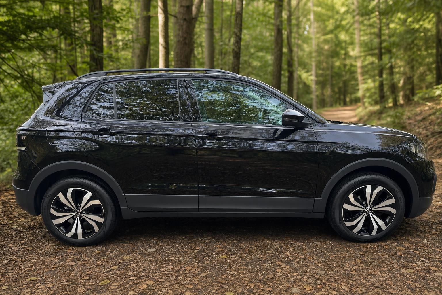 Volkswagen T-Cross SUV schwarz - Seitenansicht von rechts mit Alufelgen auf Waldweg