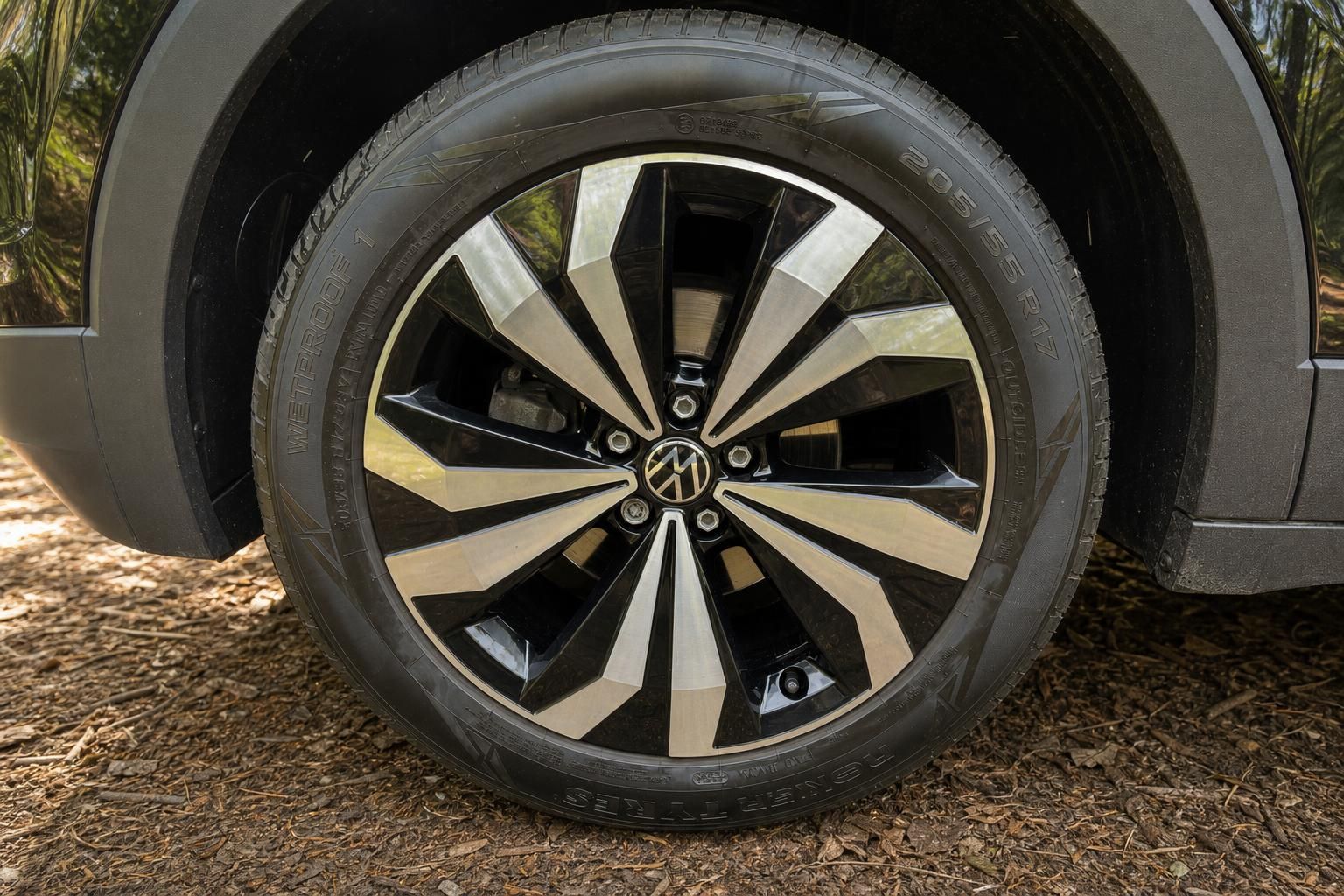 Volkswagen Alufelge mit VW-Logo, Detailaufnahme Rad mit Reifen an schwarzem SUV