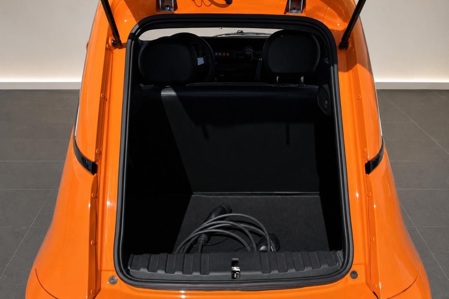 Oranges Elektroauto Kofferraum mit Ladekabel und schwarzer Innenausstattung