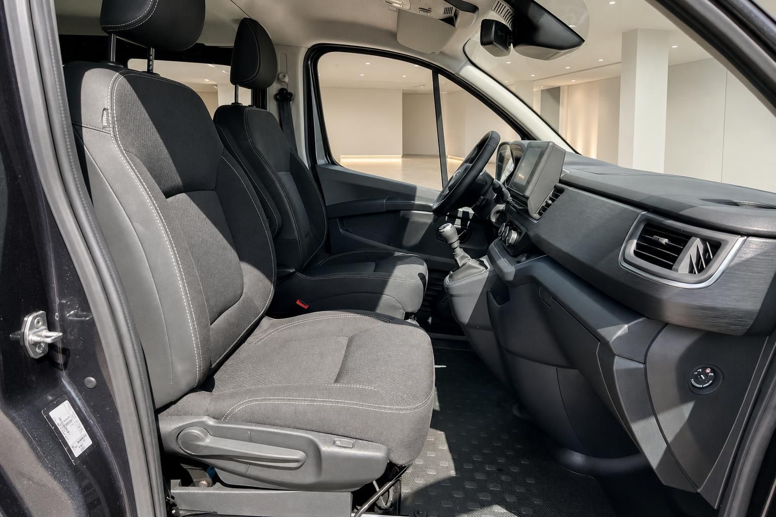 Fahrzeug-Innenraum mit grauen Stoffsitzen, Schaltknauf und schwarzem Armaturenbrett im Autohaus