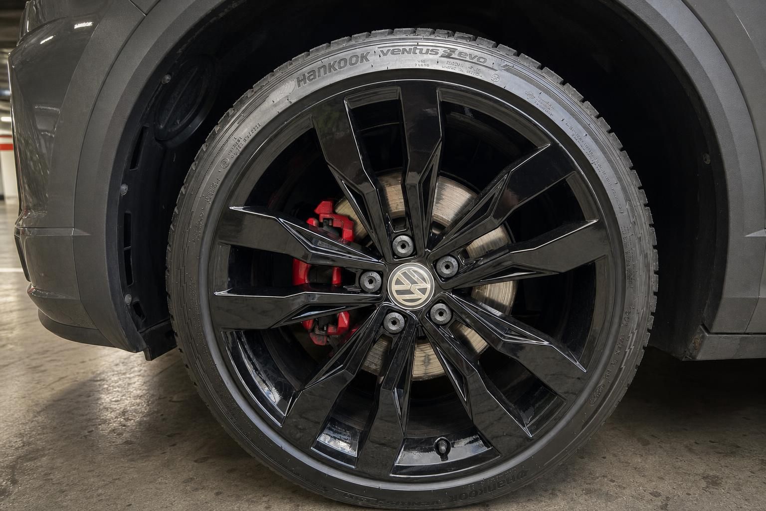 Nahaufnahme schwarze Alufelge mit rotem Bremssattel am VW