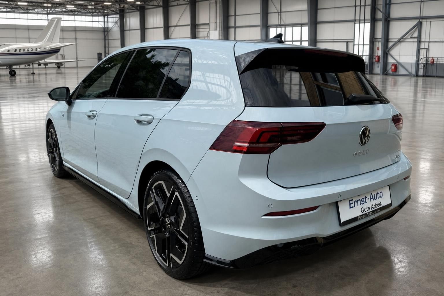 Weißer VW Golf in moderner Industriehalle - Seitenansicht von hinten rechts mit Sportfelgen