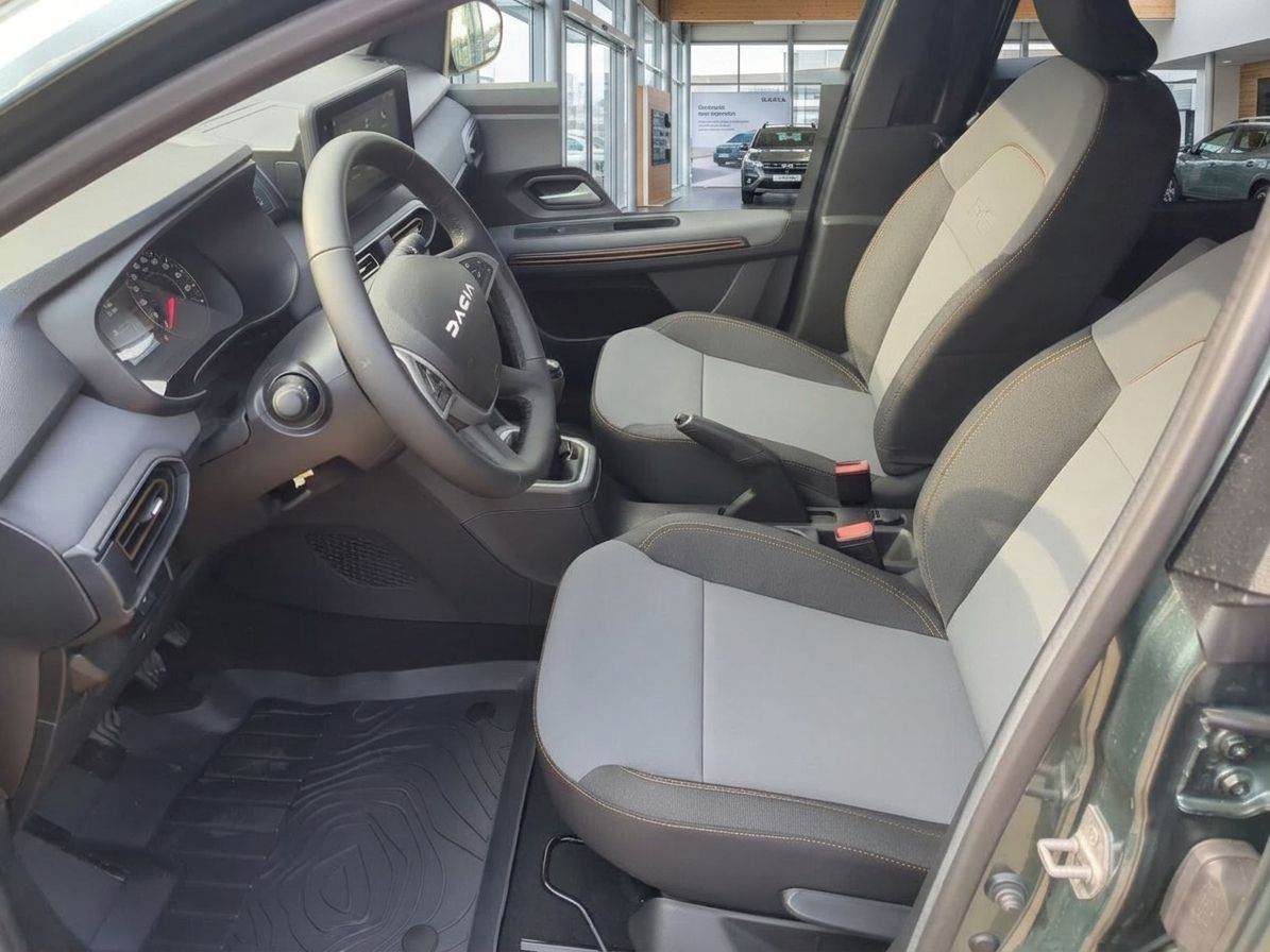 Dacia Fahrzeug Innenraum - Fahrersitz, Lenkrad und Armaturenbrett in beige-grauer Ausstattung