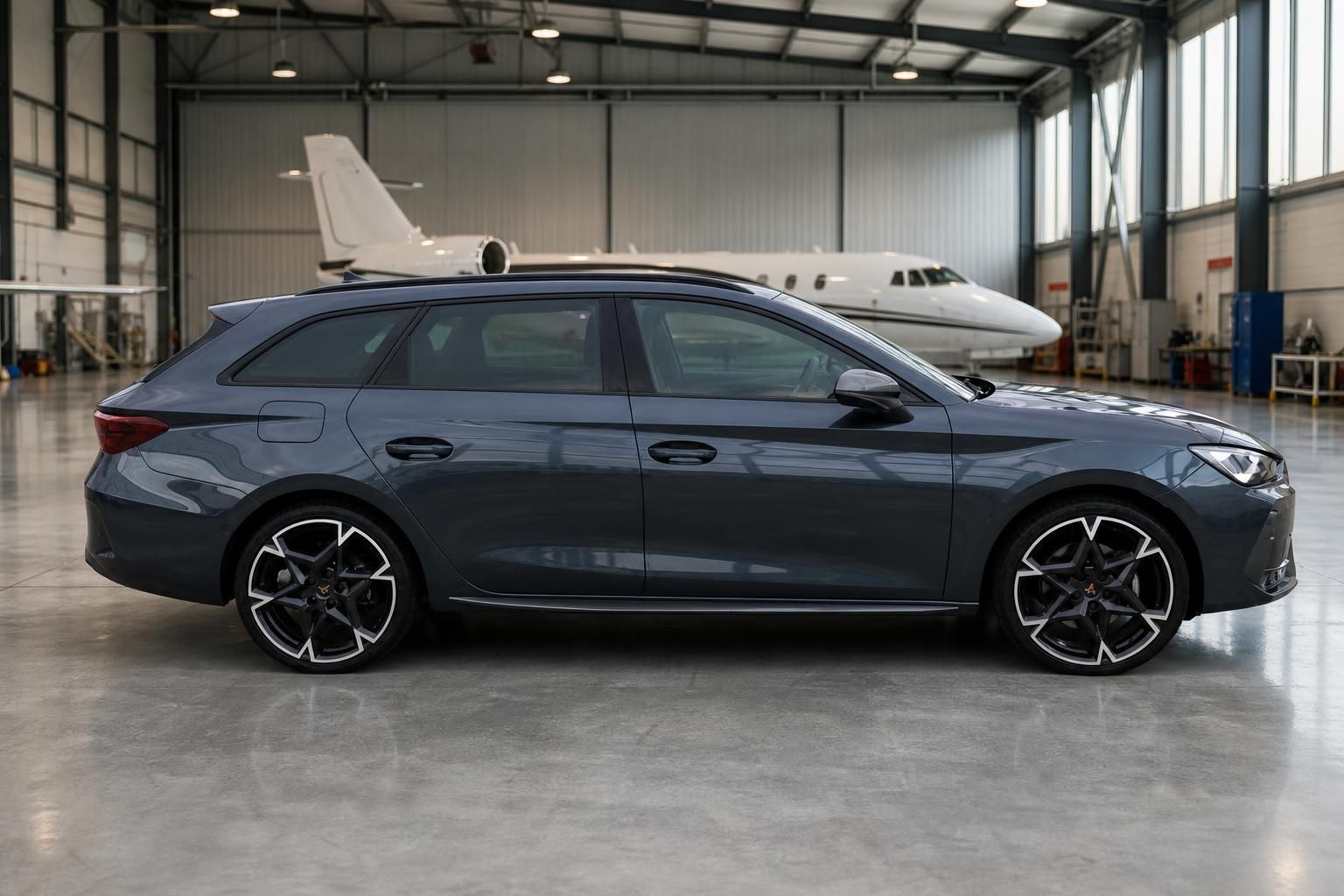 Grauer Cupra Leon Kombi Seitenansicht in Hangar mit modernen Leichtmetallfelgen