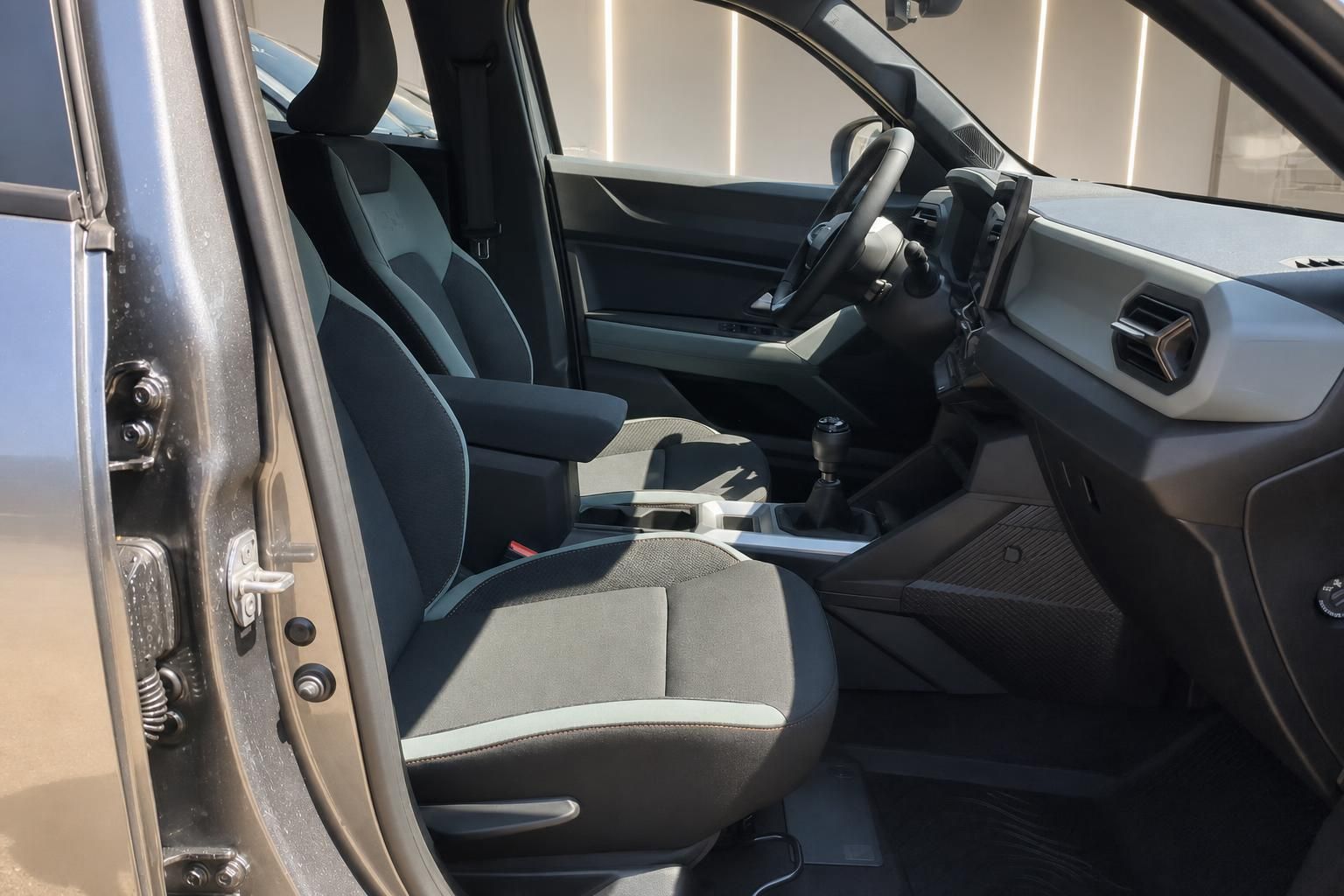 Dacia Innenraum Vordersitze mit Stoff-Polsterung und geöffneter Fahrertür