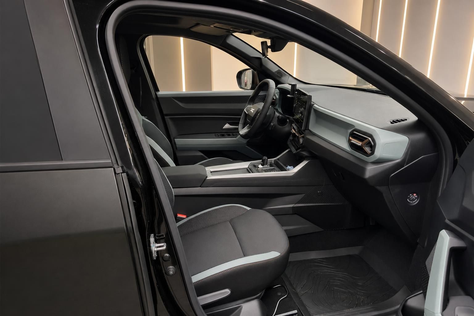 Dacia SUV Innenraum – Blick durch geöffnete Fahrertür auf Vordersitze und Armaturenbrett