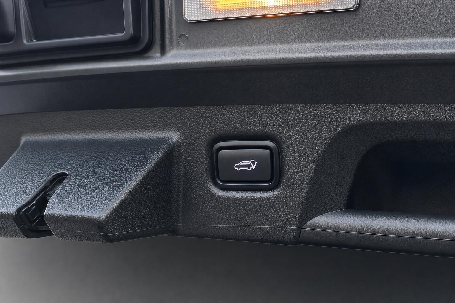 Kofferraum-Bedienknopf mit Fahrzeugsymbol im Detail des Innenraums
