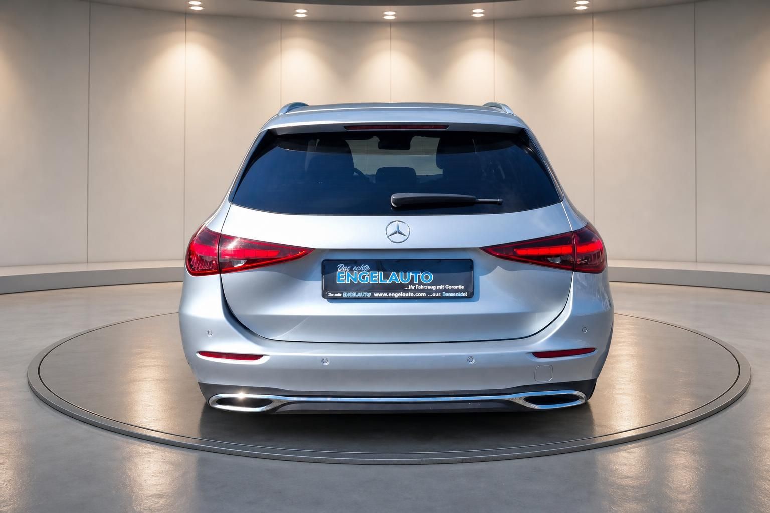 Silberner Mercedes-Benz Kombi von hinten im Showroom mit Engelauto Kennzeichenrahmen