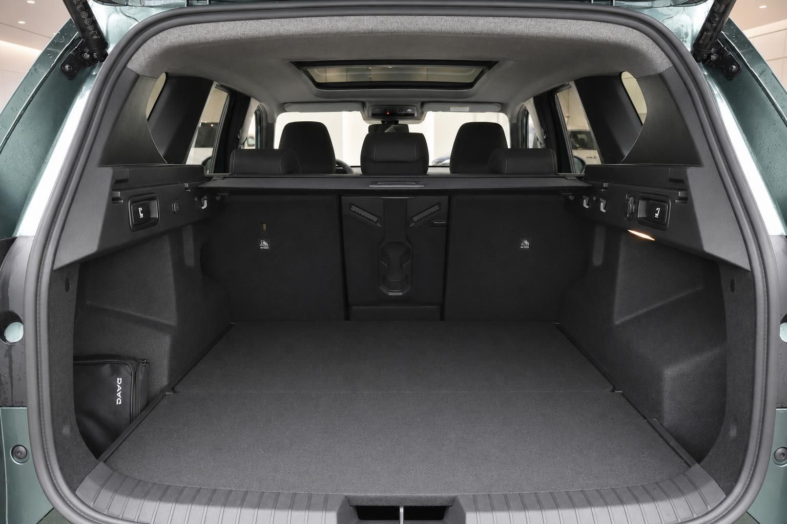 Geräumiger Kofferraum eines grünen SUV mit aufgeklappter Heckklappe und schwarzem Ladeboden