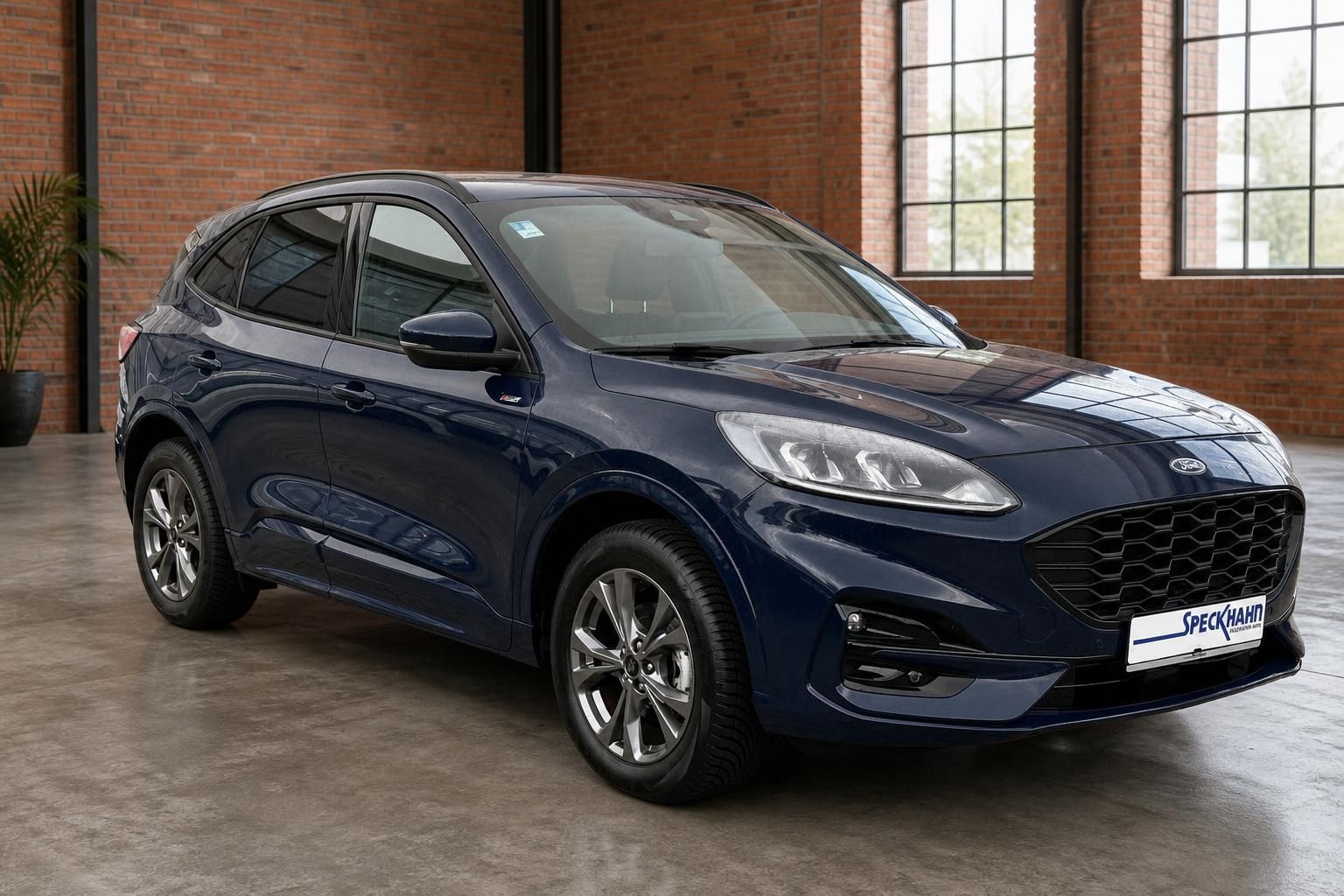 Ford Kuga dunkelblau, Frontansicht schraeg, SUV vor Backsteinfassade