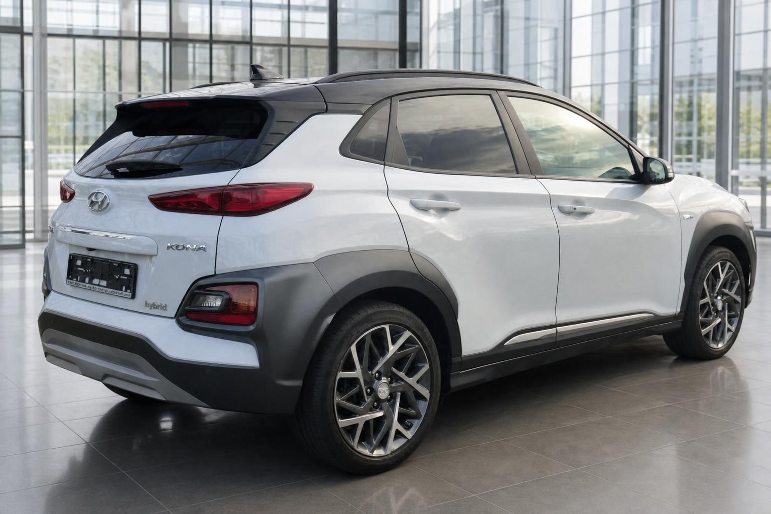 Hyundai Kona Hybrid weiss Heckansicht schräg links im Autohaus mit schwarzem Dach und Leichtmetallfelgen