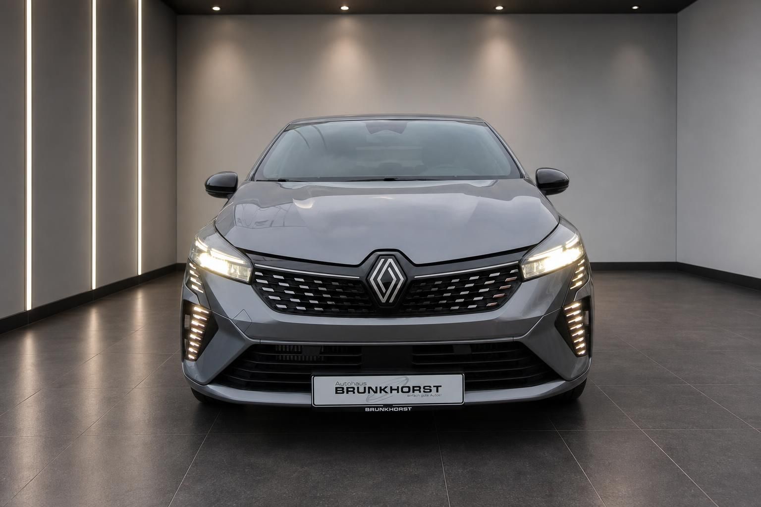 Renault Clio Frontansicht grau metallic mit LED-Tagfahrlicht im modernen Autohaus Showroom