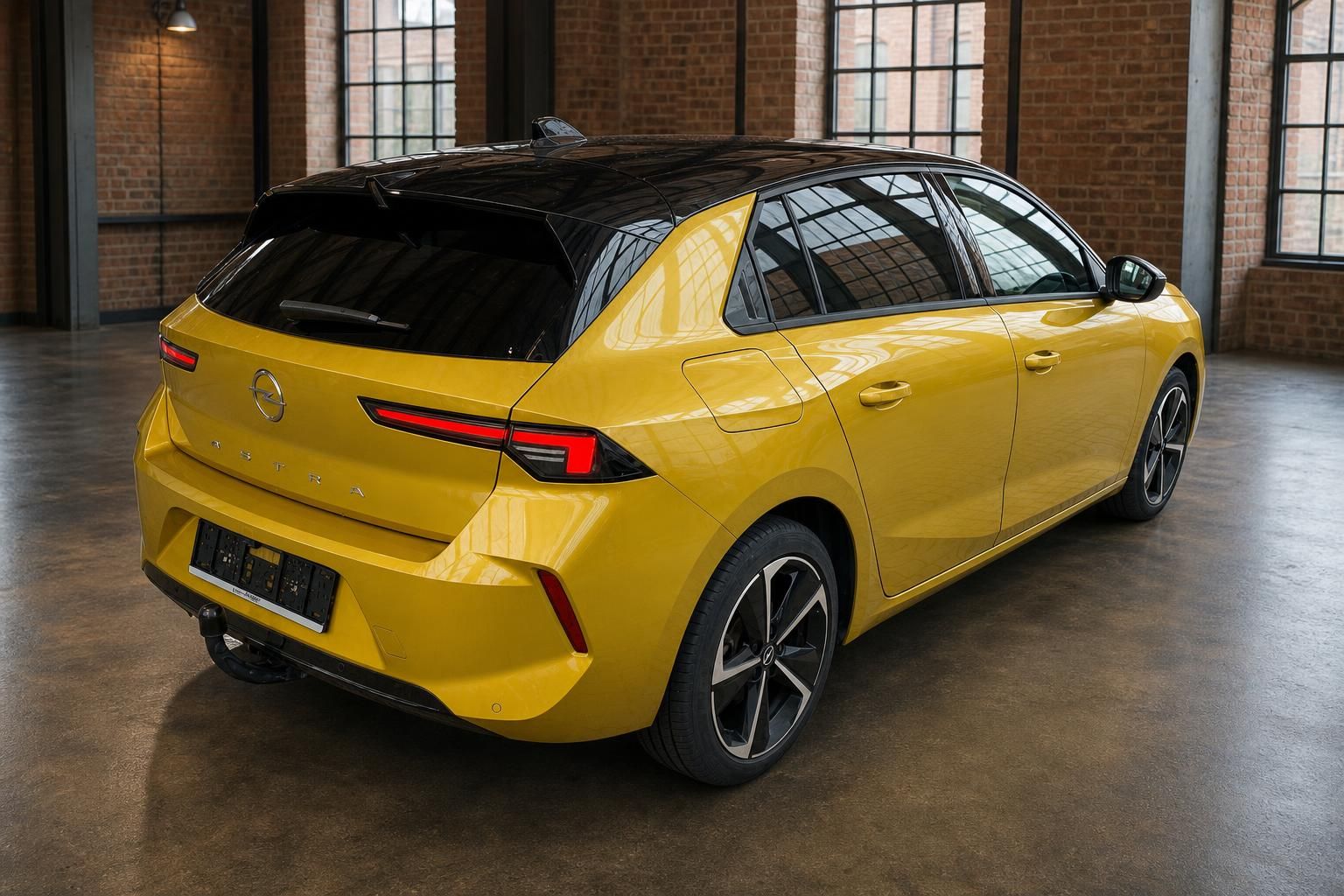 Opel Astra in Gelb, Heckansicht mit Panoramadach in Industriehalle