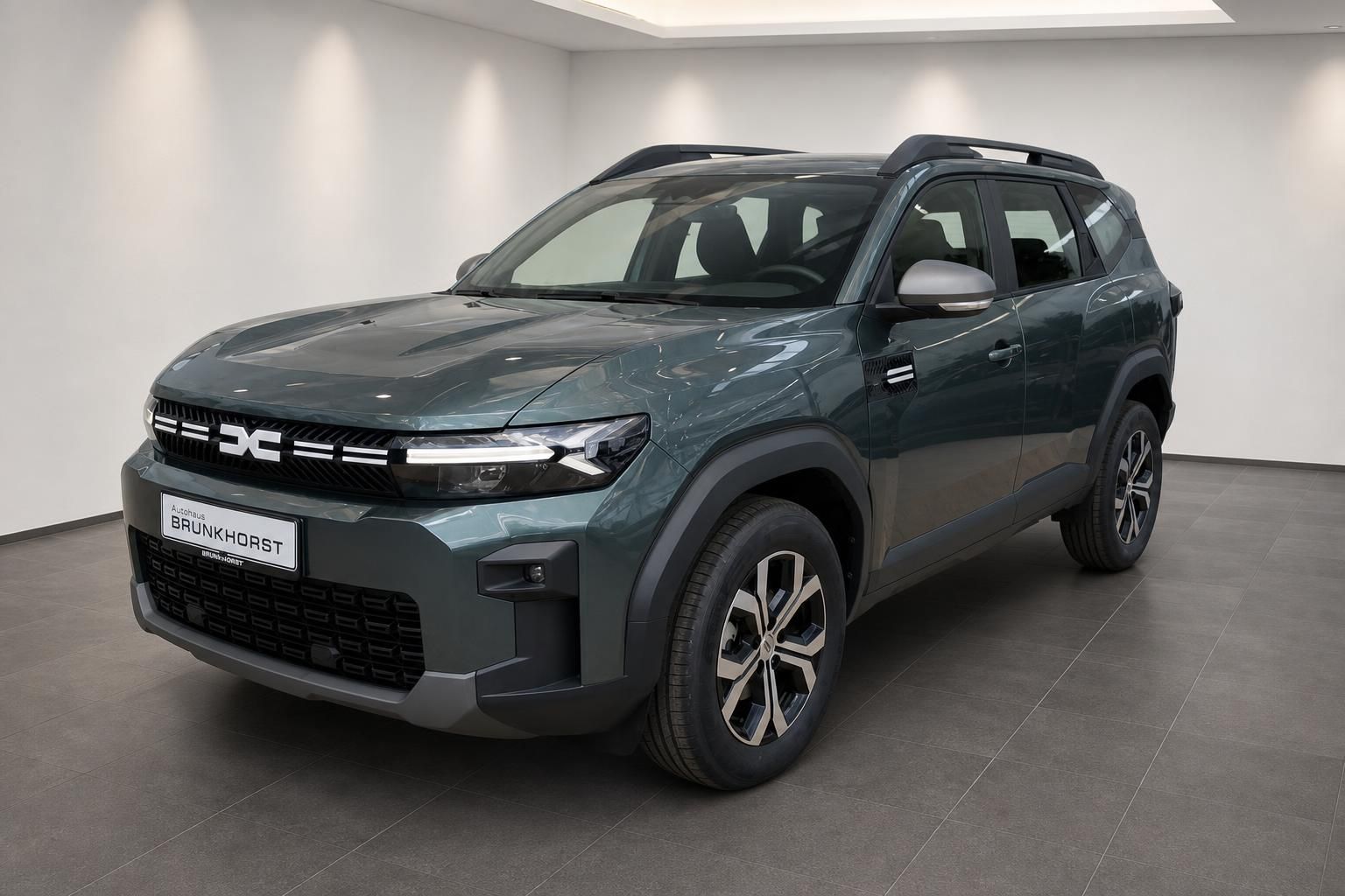 Dacia Bigster SUV in Gruen, Frontansicht schraeg im Showroom