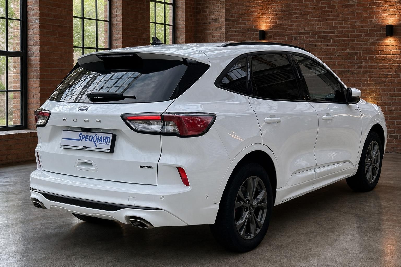 Ford Kuga weiß Heckansicht seitlich in Industriehalle mit Ziegelwand