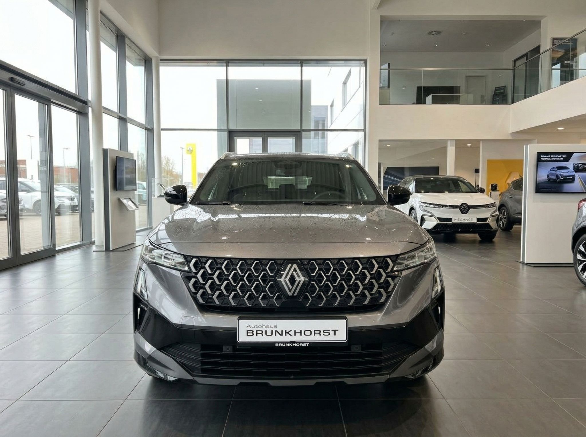 Grauer Renault SUV Frontansicht im hellen Autohaus-Showroom mit großen Fensterfronten