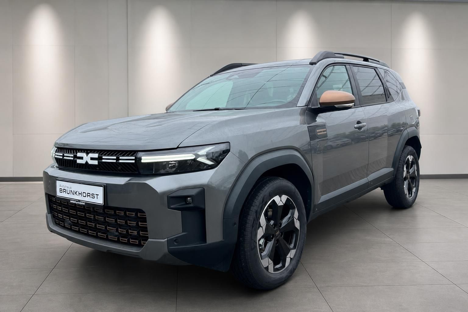 Dacia SUV Seitenansicht grau mit Dachreling und Leichtmetallfelgen im Showroom