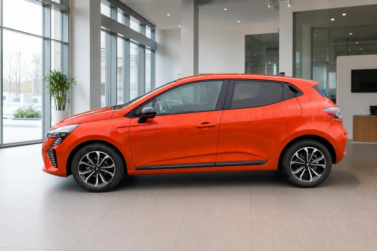 Roter Renault Clio Seitenansicht mit Leichtmetallfelgen in modernem Autohaus