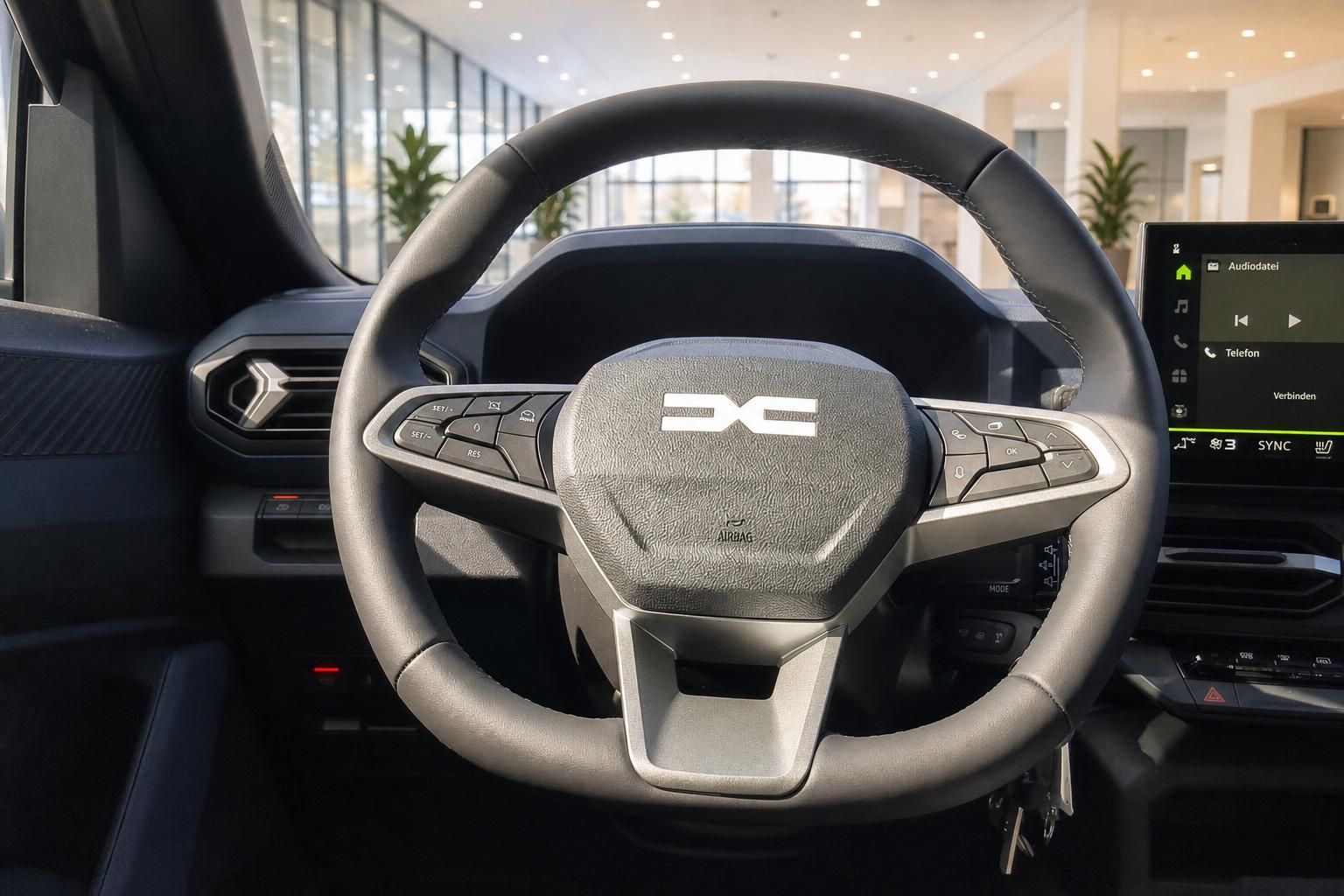 Lenkrad mit Multifunktionstasten und Infotainment-Display im Fahrzeuginnenraum