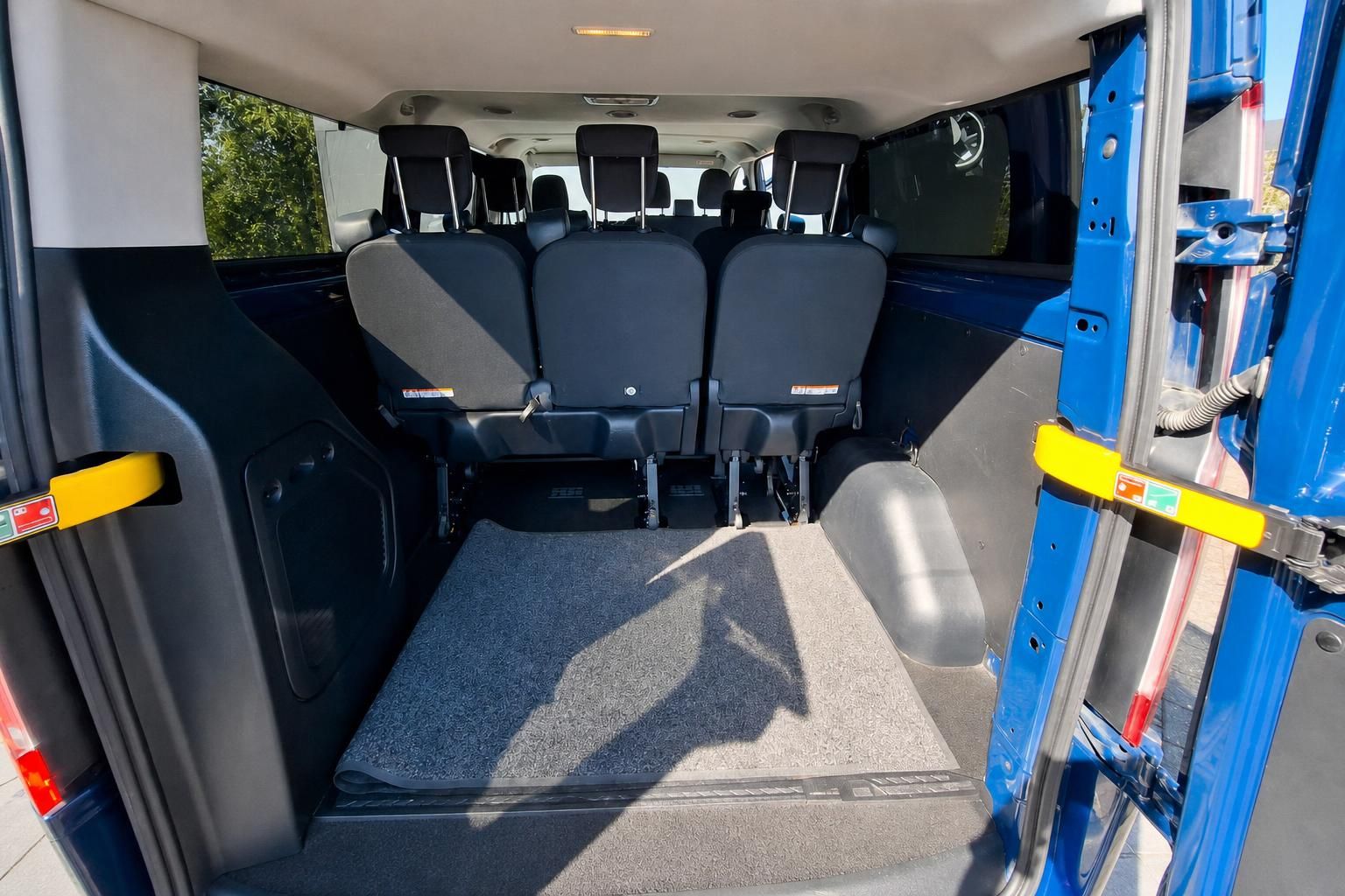 Ford Transit Innenraum von hinten mit Sitzreihen und offener Schiebetür