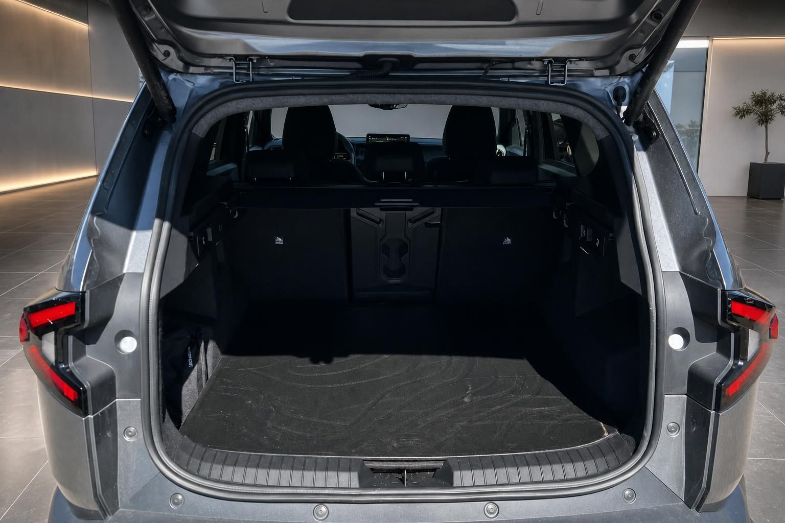 Geöffneter Kofferraum eines grauen SUV mit schwarzer Ladekante in modernem Showroom