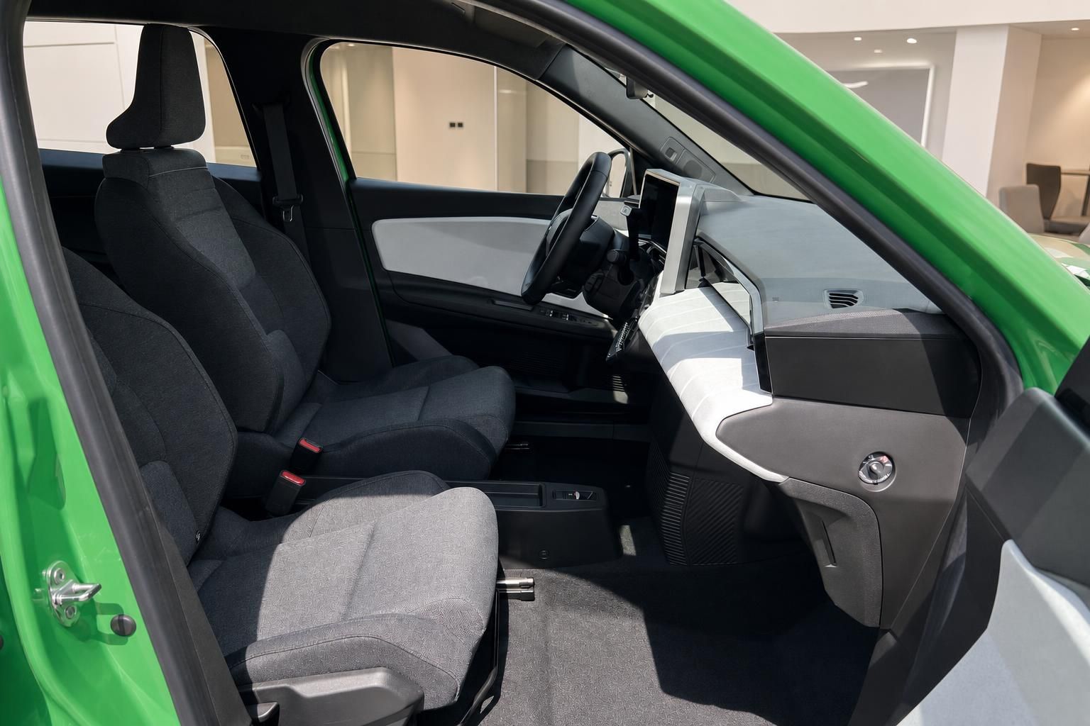 Grünes Elektroauto Innenraum – Vordersitze und Cockpit mit geöffneter Fahrertür im Autohaus