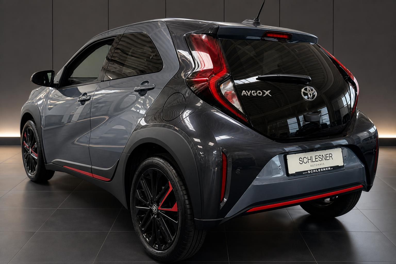 Toyota Aygo X in Grau, Heckansicht mit rotem Akzent im Autohaus