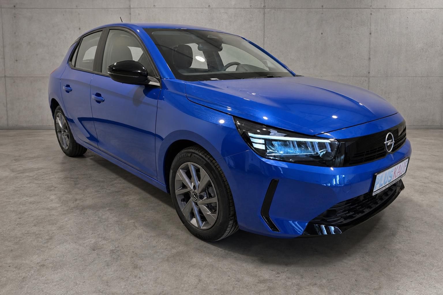Opel Corsa blau, Frontansicht schräg vor Betonwand
