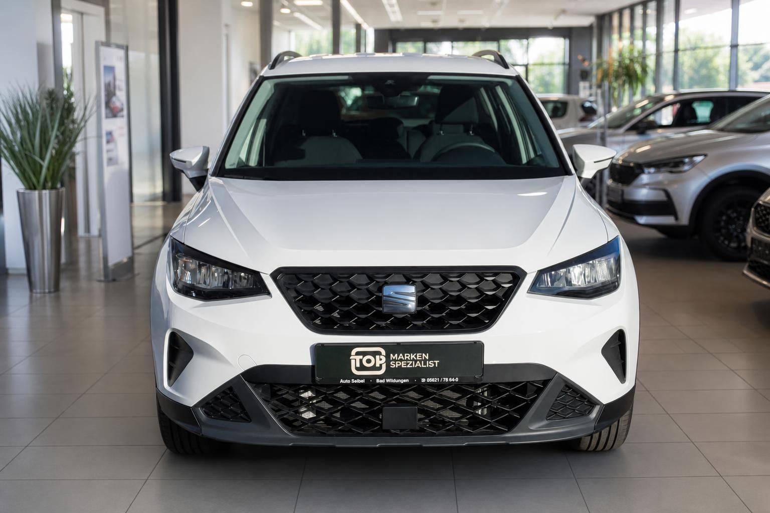 Weißer SEAT SUV Frontansicht im Autohaus-Showroom mit LED-Scheinwerfern und schwarzem Kühlergrill