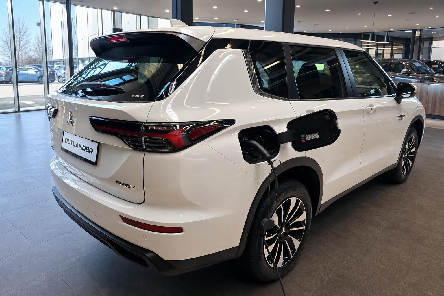 Mitsubishi Outlander PHEV weiß beim Laden, Heckansicht im Showroom