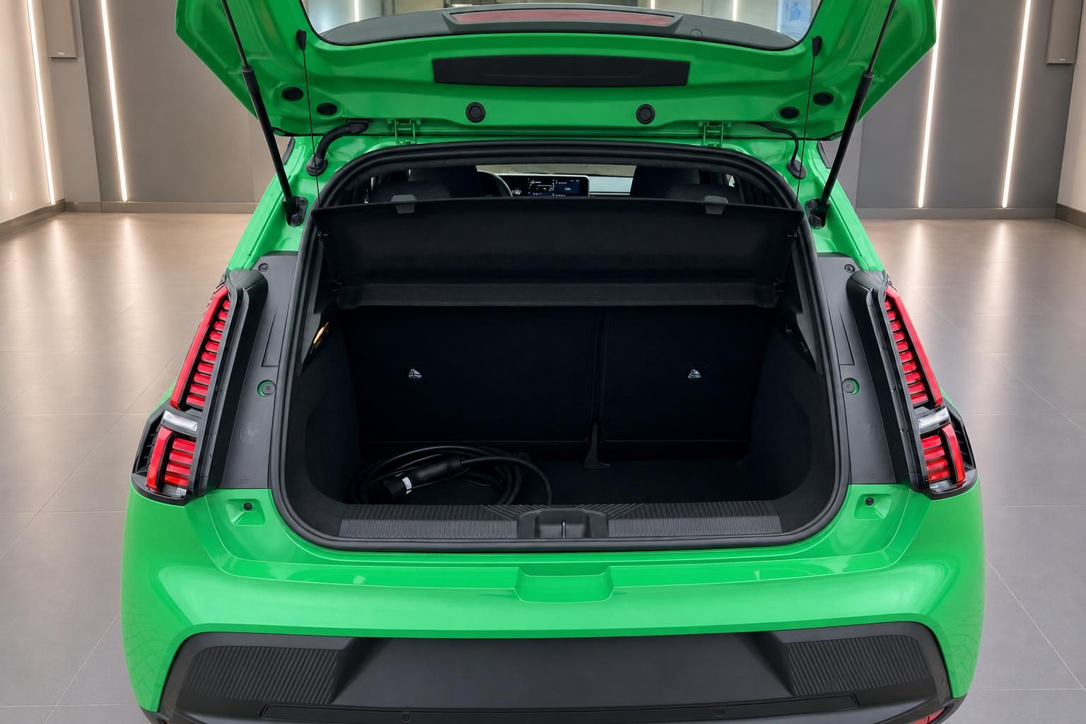 Kofferraum eines grünen Elektroautos mit geöffneter Heckklappe und Ladekabel